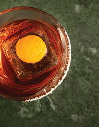 Negroni in a tumbler with a orange peel frozen in a block of ice top view down